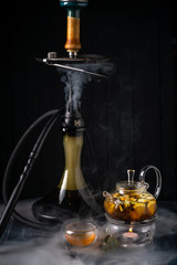 Tea kettle with lemon and Smoking hookah. Traditional Arabian shisha with tea