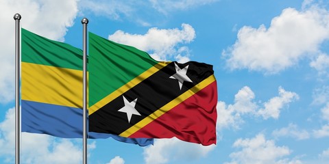 Gabon and Saint Kitts And Nevis flag waving in the wind against white cloudy blue sky together. Diplomacy concept, international relations.
