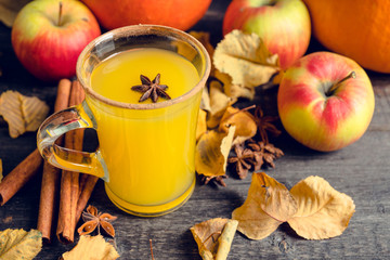 Autumn hot and spicy drink with pumpkin and orange juice on the rustic background. Selective focus. Shallow depth of field.