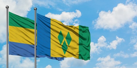 Gabon and Saint Vincent And The Grenadines flag waving in the wind against white cloudy blue sky together. Diplomacy concept, international relations.