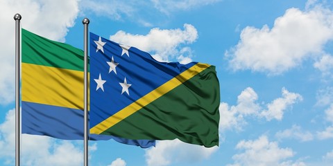 Gabon and Solomon Islands flag waving in the wind against white cloudy blue sky together. Diplomacy concept, international relations.