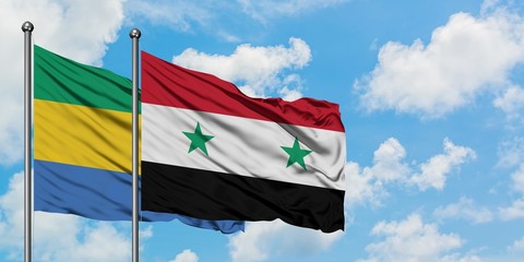 Gabon and Syria flag waving in the wind against white cloudy blue sky together. Diplomacy concept, international relations.