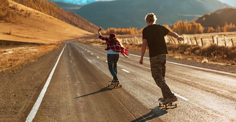 Young couple riding on longboards