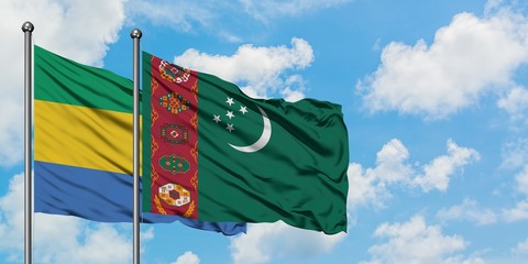 Gabon and Turkmenistan flag waving in the wind against white cloudy blue sky together. Diplomacy...