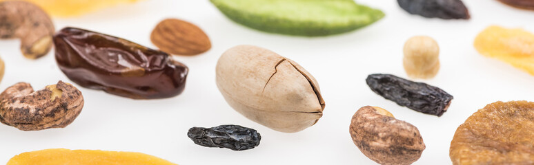 close up view of tasty assorted nuts, dried fruits and candied fruit isolated on white, panoramic shot