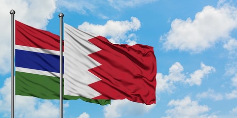 Gambia and Bahrain flag waving in the wind against white cloudy blue sky together. Diplomacy concept, international relations.