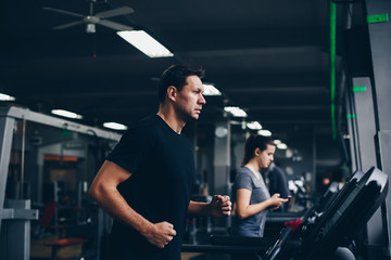 Fototapeta na wymiar authentic image of attractive man running on the treadmill in the gym. concept of weight los and active living.