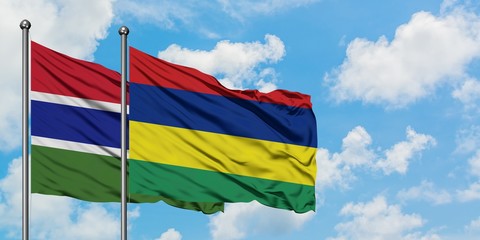 Gambia and Mauritius flag waving in the wind against white cloudy blue sky together. Diplomacy concept, international relations.