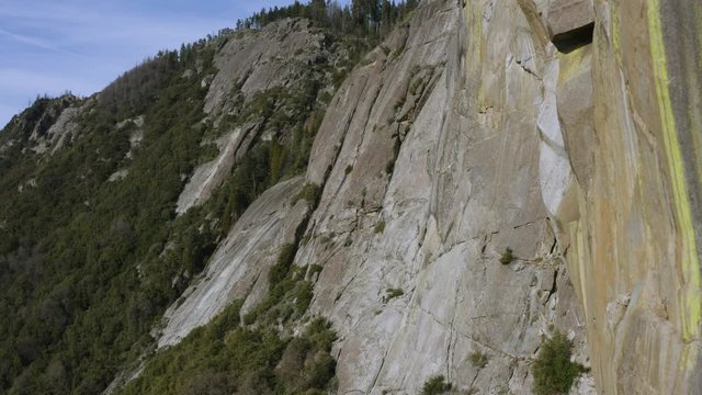 Aerial shot flying along a massive granite wall found on the rocky peak of one of the Sierra Nevada Mountain Tops.