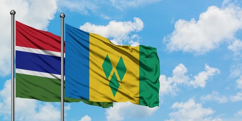 Gambia and Saint Vincent And The Grenadines flag waving in the wind against white cloudy blue sky together. Diplomacy concept, international relations.
