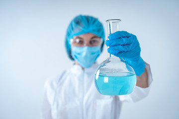 Laborant woman holding medical glass bottle with liquid, making laboratory analysis