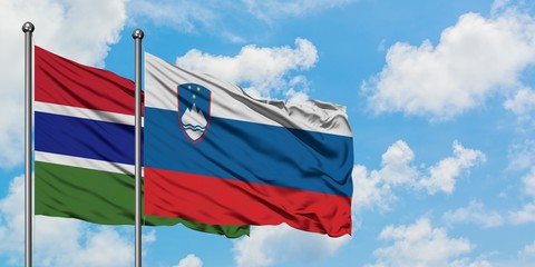 Gambia and Slovenia flag waving in the wind against white cloudy blue sky together. Diplomacy concept, international relations.