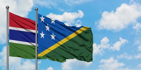 Gambia and Solomon Islands flag waving in the wind against white cloudy blue sky together. Diplomacy concept, international relations.
