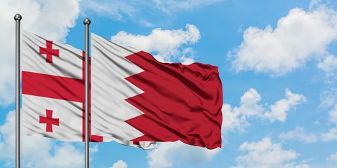 Georgia and Bahrain flag waving in the wind against white cloudy blue sky together. Diplomacy concept, international relations.