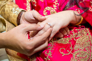 Obraz na płótnie Canvas Bride places the wedding ring on the Groom’s finger at Bangladesh. Close up image.