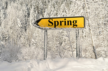 Road sign arrow pinting to spring in the middle of snowy country