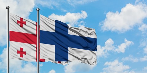 Georgia and Finland flag waving in the wind against white cloudy blue sky together. Diplomacy concept, international relations.