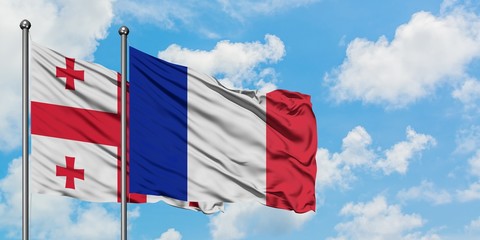 Georgia and France flag waving in the wind against white cloudy blue sky together. Diplomacy concept, international relations.