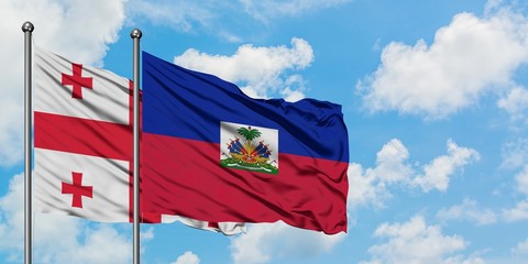 Georgia and Haiti flag waving in the wind against white cloudy blue sky together. Diplomacy concept, international relations.