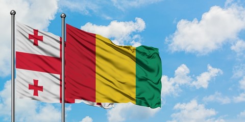 Georgia and Guinea flag waving in the wind against white cloudy blue sky together. Diplomacy concept, international relations.