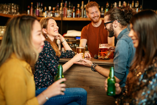 Group Of Friends Drinking Beer, Chatting And Having Good Time At Pub. Night Out.