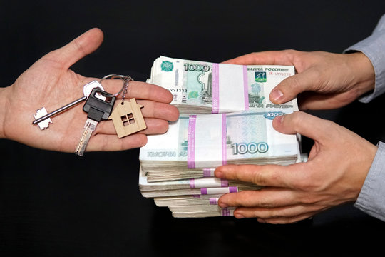 Banknotes of Russian rubles and keys to the apartment on black table. Estate sale. The deal for the sale of apartment. Concept real estate transaction