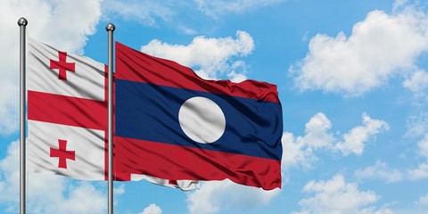 Georgia and Laos flag waving in the wind against white cloudy blue sky together. Diplomacy concept, international relations.