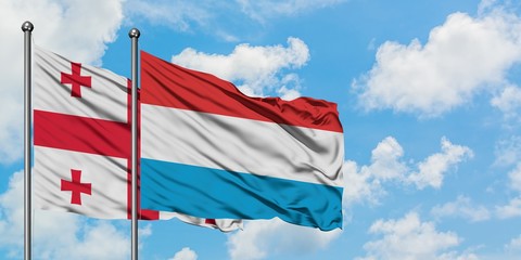 Georgia and Luxembourg flag waving in the wind against white cloudy blue sky together. Diplomacy concept, international relations.