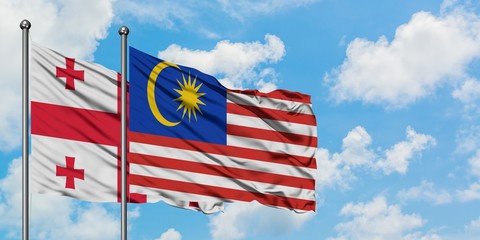Georgia and Malaysia flag waving in the wind against white cloudy blue sky together. Diplomacy concept, international relations.