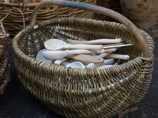 Objects of folk crafts. Wooden spoons carved from Linden chocks in a basket woven from willow vines.