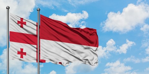 Georgia and Monaco flag waving in the wind against white cloudy blue sky together. Diplomacy concept, international relations.