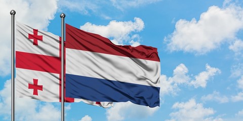 Georgia and Netherlands flag waving in the wind against white cloudy blue sky together. Diplomacy concept, international relations.
