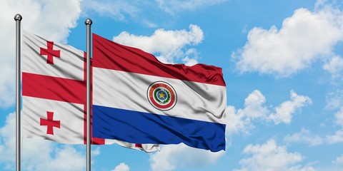 Georgia and Paraguay flag waving in the wind against white cloudy blue sky together. Diplomacy concept, international relations.
