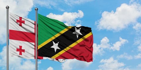 Georgia and Saint Kitts And Nevis flag waving in the wind against white cloudy blue sky together. Diplomacy concept, international relations.