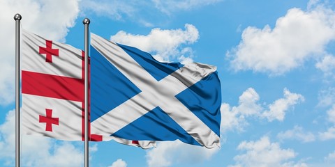 Georgia and Scotland flag waving in the wind against white cloudy blue sky together. Diplomacy concept, international relations.