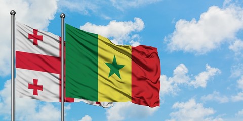 Georgia and Senegal flag waving in the wind against white cloudy blue sky together. Diplomacy concept, international relations.