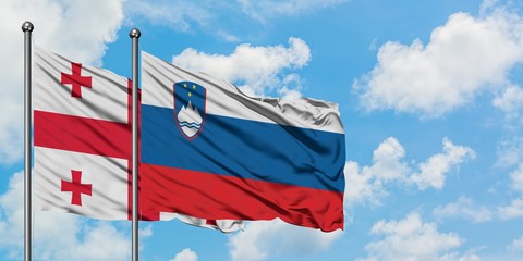 Georgia and Slovenia flag waving in the wind against white cloudy blue sky together. Diplomacy concept, international relations.