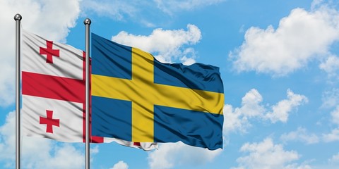 Georgia and Sweden flag waving in the wind against white cloudy blue sky together. Diplomacy concept, international relations.