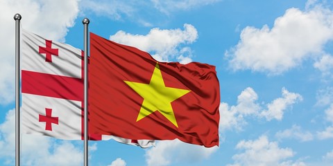 Georgia and Vietnam flag waving in the wind against white cloudy blue sky together. Diplomacy concept, international relations.