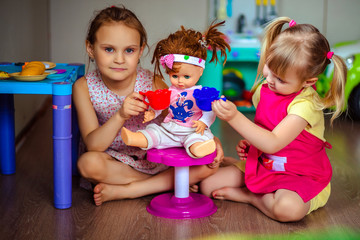two little girls playing with a doll