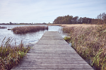 Obraz premium Retro toned picture of a wooden pier by lake in Autumn