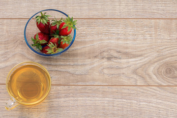 Glass cup of green tea and stawberries on wooden background.