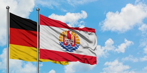 Germany and French Polynesia flag waving in the wind against white cloudy blue sky together. Diplomacy concept, international relations.