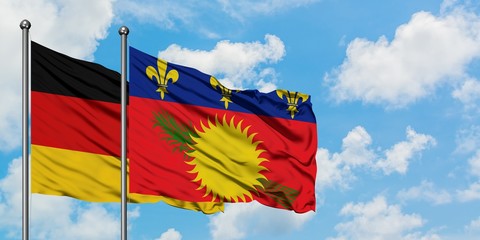 Germany and Guadeloupe flag waving in the wind against white cloudy blue sky together. Diplomacy concept, international relations.