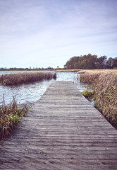 Retro toned picture of a wooden pier by lake in Autumn