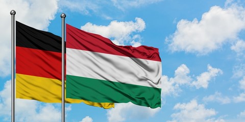 Germany and Hungary flag waving in the wind against white cloudy blue sky together. Diplomacy concept, international relations.