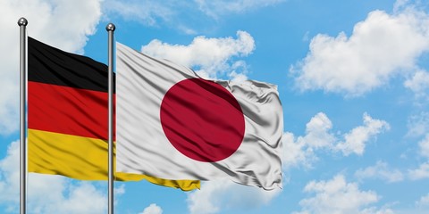 Germany and Japan flag waving in the wind against white cloudy blue sky together. Diplomacy concept, international relations.