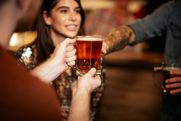 Man standing in group and giving beer to a friend. Irish pub interior. Nightlife.