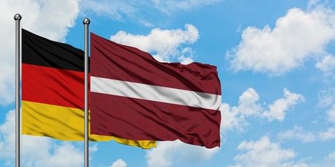 Germany and Latvia flag waving in the wind against white cloudy blue sky together. Diplomacy concept, international relations.