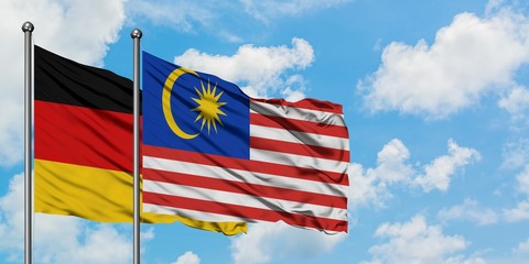 Germany and Malaysia flag waving in the wind against white cloudy blue sky together. Diplomacy concept, international relations.
